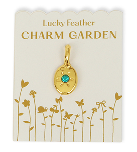 A gold charm with a turquoise stone on a 'Lucky Feather Charm Garden' card with floral designs.