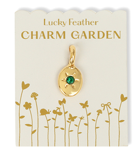 The image shows a 'Lucky Feather Charm Garden' charm with a gold oval pendant and a green gem on a decorated white card.