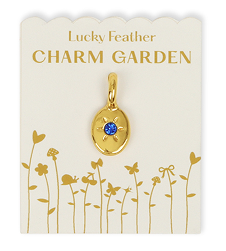 Gold-colored charm with blue stone on a Lucky Feather Charm Garden card.