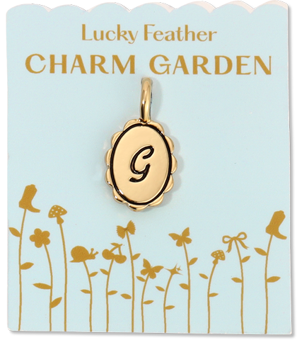 A charm with the letter 'G' on a floral-themed card.
