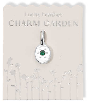 Silver charm pendant with a green gem on a 'Lucky Feather Charm Garden' card with floral designs.