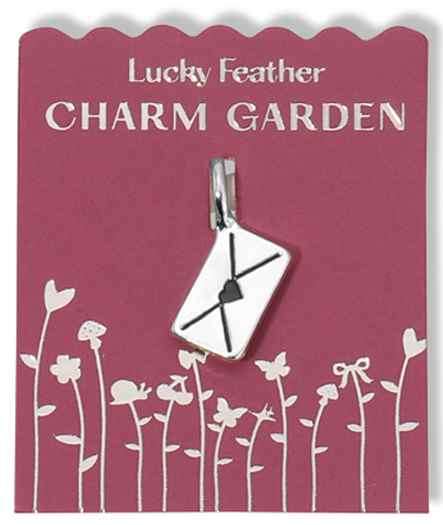A 'Lucky Feather Charm Garden' charm of an envelope with a heart on it is displayed on a pink scalloped card with silver flower and garden designs.