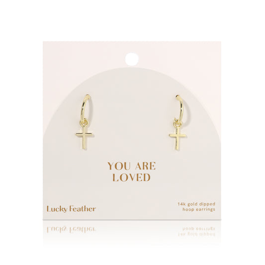 Display of 'Lucky Feather' 14K gold dipped hoop earrings with cross charms.
