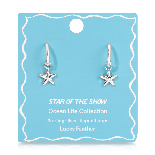 A pair of silver hoop earrings with starfish charms on a blue display card.