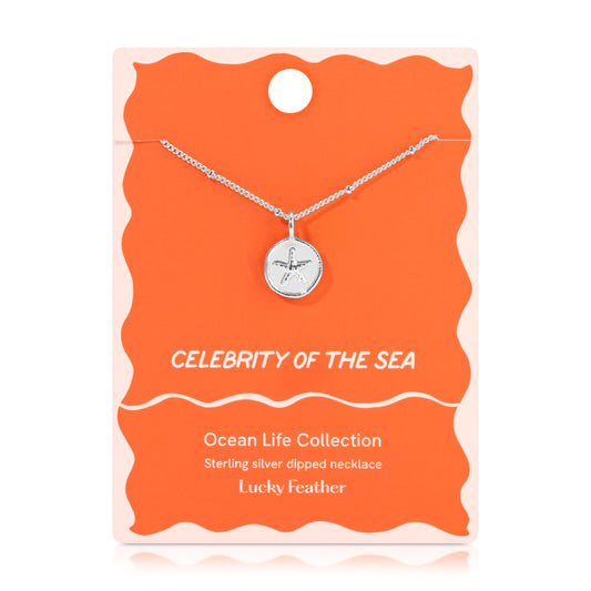 A sterling silver necklace with a starfish pendant on a coral-colored display card.
