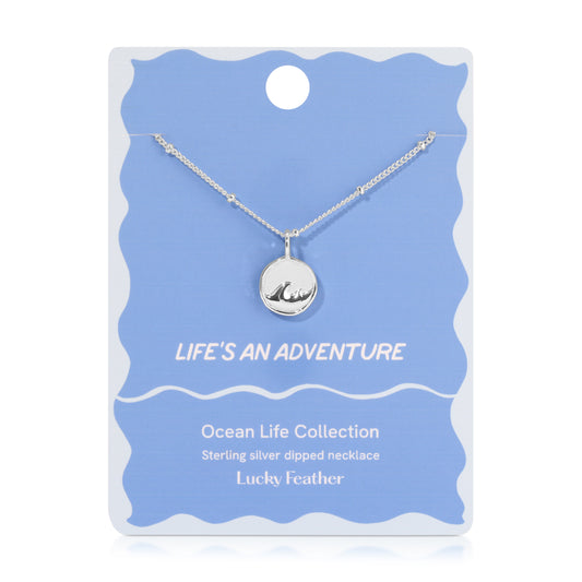 A sterling silver ocean wave necklace on a blue and white display card.