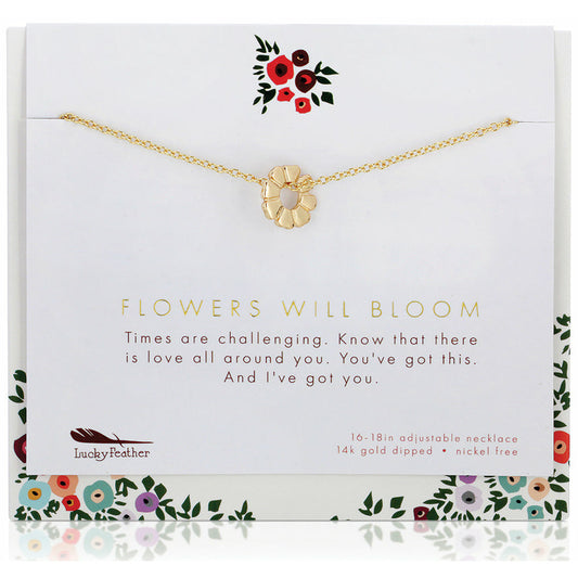A gold-colored flower pendant necklace on a card with the text 'Flowers Will Bloom.'