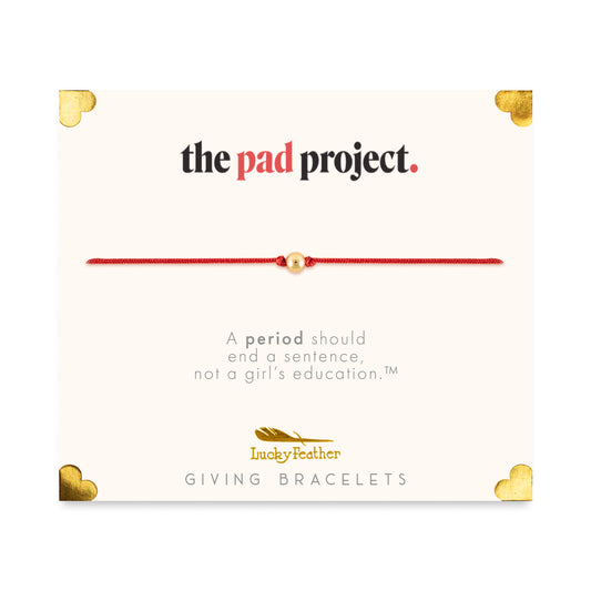 Promotional card for 'The Pad Project' by Lucky Feather Giving Bracelets, featuring a red string bracelet with a gold bead.