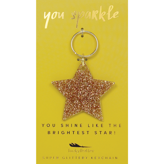 A glittery gold star keychain on a yellow card.