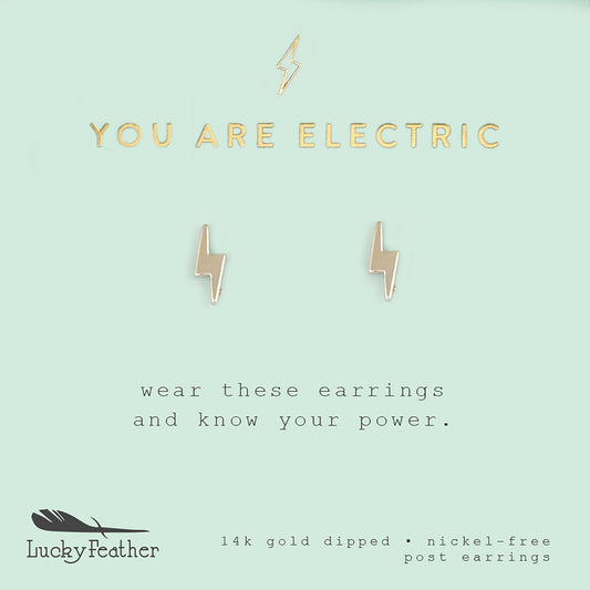 A pair of gold lightning bolt earrings are centered on a light blue card with the text 'YOU ARE ELECTRIC' above them.