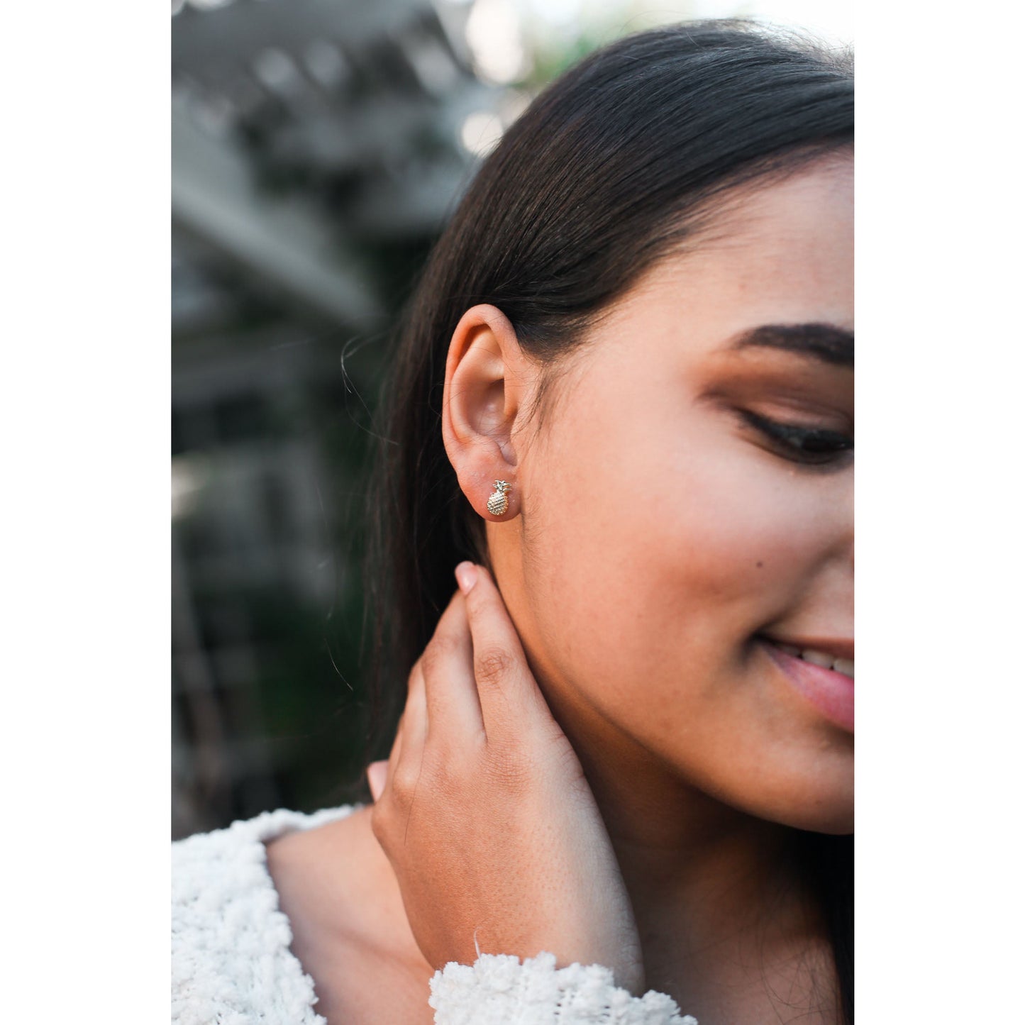 Close-up of a smiling person wearing a pineapple earring.