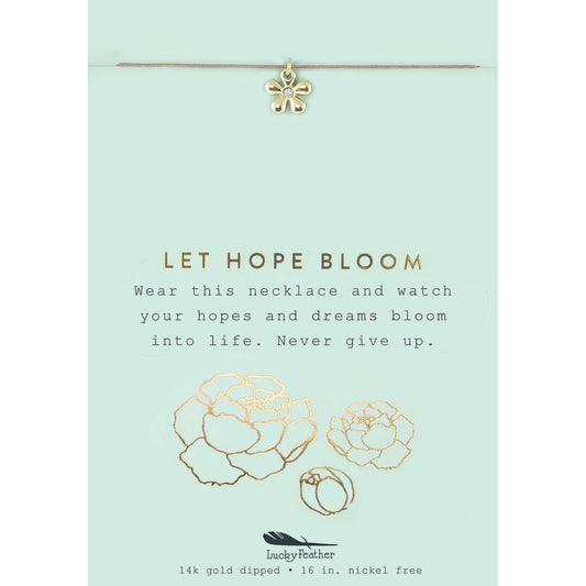 A gold flower pendant hangs from a necklace on a card that reads 'LET HOPE BLOOM.'