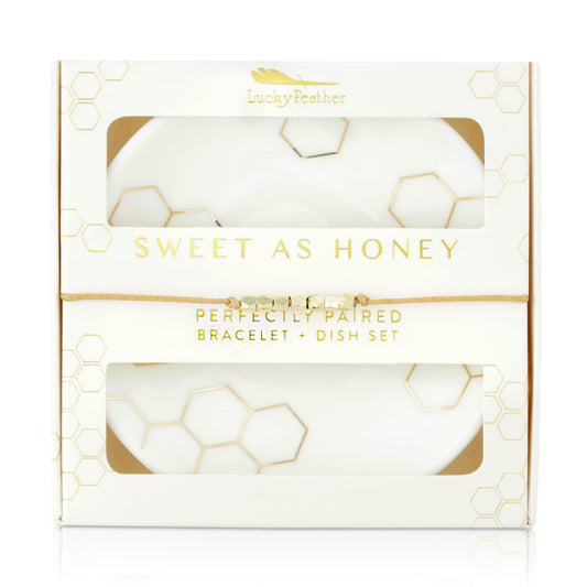 The image shows a boxed gift set with 'Sweet As Honey' and 'Perfectly Paired Bracelet + Dish Set' printed on the box, displaying a bracelet and dishes with a honeycomb design.